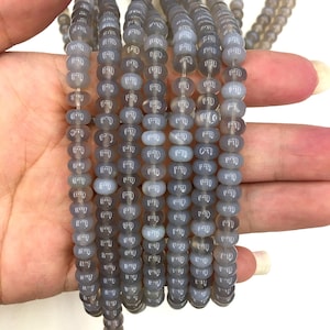 May include: A strand of grey agate beads with a smooth, polished finish. Each bead has a white inscription.