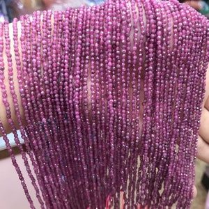 May include: A strand of ruby beads, each bead is faceted and has a deep pink color. The beads are strung on a thin wire and are approximately 2 mm in diameter.