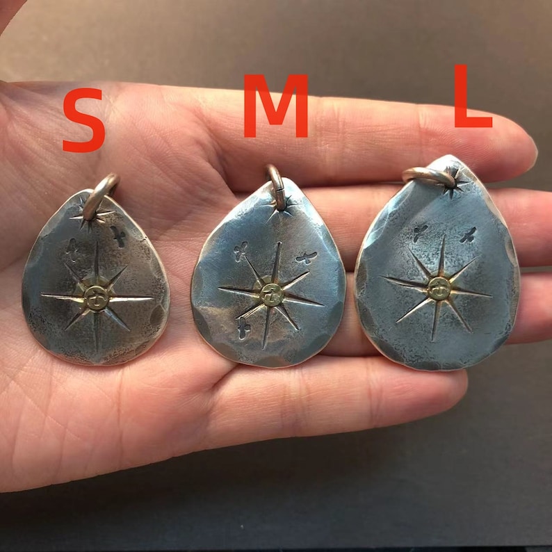 May include: Three silver pendants with a star design and a gold center. The pendants are labeled S, M, and L, indicating their size.