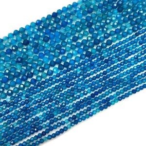 May include: A strand of blue faceted gemstone beads. The beads are round and have a smooth, polished finish.
