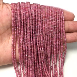 May include: A strand of pink tourmaline beads, each bead is a square shape with a faceted finish. The beads are strung on a clear thread and are approximately 2mm in size.