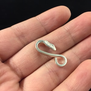 Puede incluir: Gancho de metal plateado con un diseño decorativo de cabeza de serpiente estilizada.