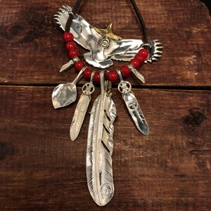 May include: Silver necklace with a large eagle pendant, red beads, and multiple feather charms.