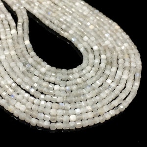May include: A strand of white moonstone beads, each bead is square shaped and has a slight iridescent shimmer.