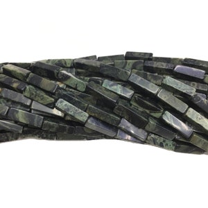 May include: A strand of dark green and black gemstone beads, each bead is a rectangular prism with a marbled pattern.