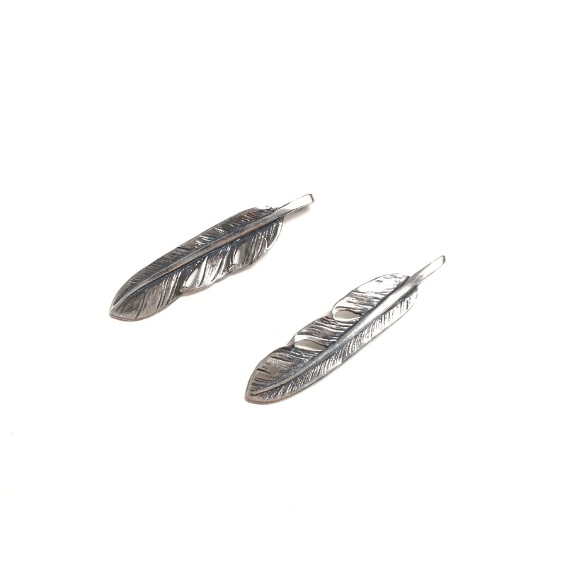 Puede incluir: Dos abalorios de plumas de plata con dise&ntilde;os de plumas detallados.