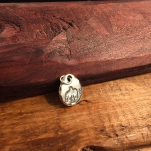 K&ouml;nnte beinhalten: Silberner Anh&auml;nger mit Vogelmotiv. Der Anh&auml;nger ist oval geformt und hat eine strukturierte Oberfl&auml;che. Auf der R&uuml;ckseite des Anh&auml;ngers ist die Nummer "925" eingepr&auml;gt.