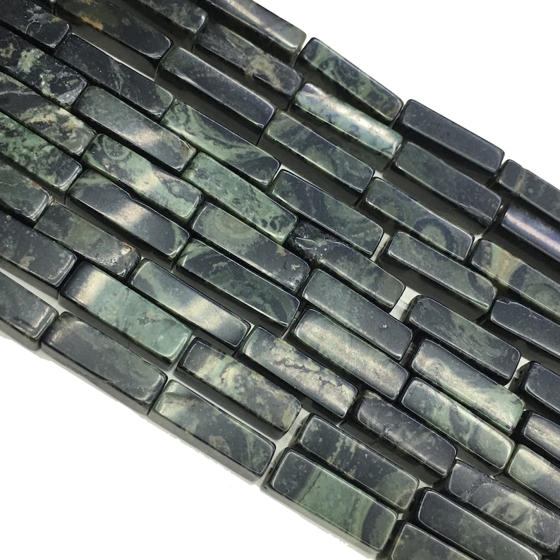 May include: A strand of dark green and black gemstone beads, each bead is a rectangular prism with a marbled pattern.