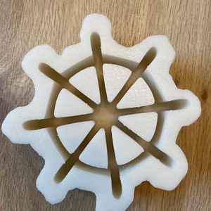 以下が含まれることがあります： 8本のスポークを持つ船の舵の形をした白いプラスチック製の型