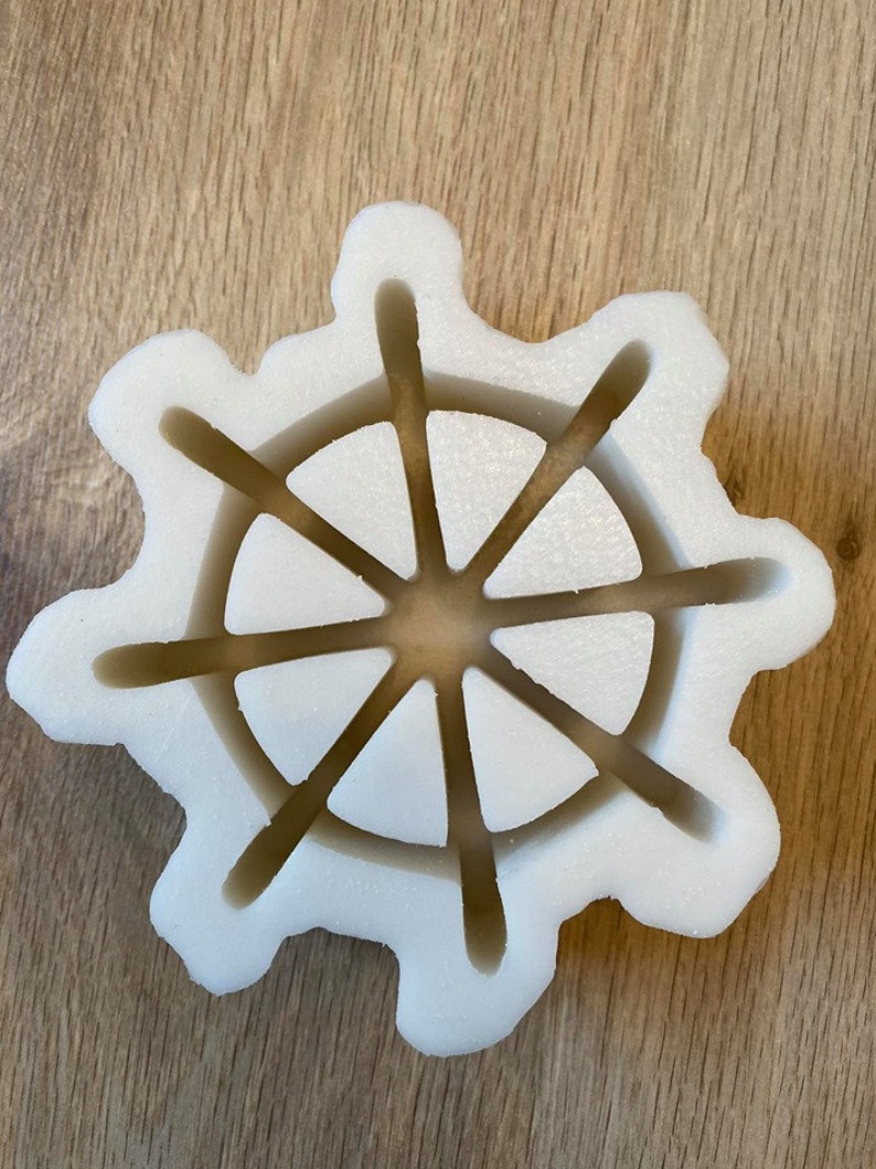 以下が含まれることがあります： 8本のスポークを持つ船の舵の形をした白いプラスチック製の型