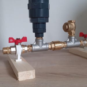 May include: A plumbing system with two valves and a filter. The valves are brass with red handles and the filter is gray. The system is mounted on two wooden boards.