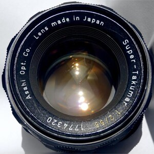 May include: A black camera lens with the text "Asahi Opt. Co. Lens made in Japan Super-Takumar 1:2/55 177320" printed around the edge.