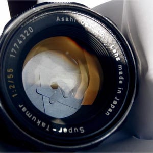 May include: A black Super-Takumar 1:2.1/55 1774320 lens with the text "Asahi Optical Co. Lens made in Japan" printed on the side.