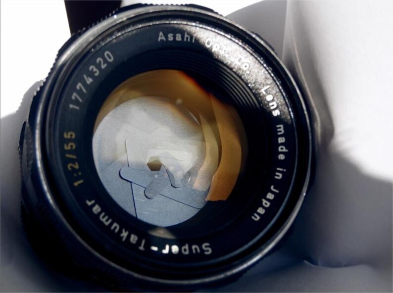 May include: A black Super-Takumar 1:2.1/55 1774320 lens with the text "Asahi Optical Co. Lens made in Japan" printed on the side.