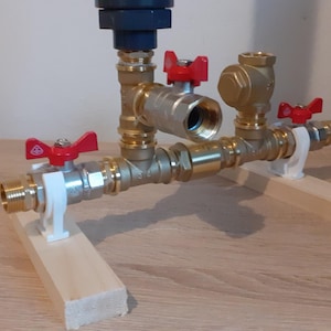 May include: A plumbing system with four brass valves and red handles, mounted on two wooden supports.