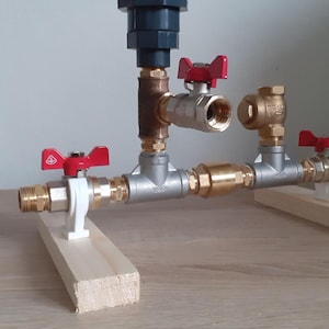 May include: A plumbing system with four valves and red handles. The valves are connected with pipes and mounted on two wooden boards.