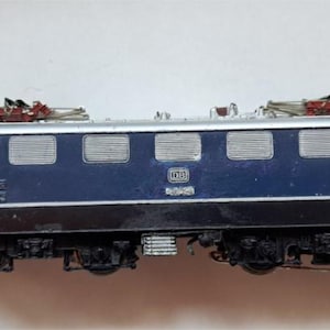 Könnte beinhalten: Ein Modell einer Lokomotive in Blau, Silber und Schwarz. Der Miniaturzug hat mehrere Fenster, komplizierte Details und elektrische Oberleitungskomponenten. Eine Nachbildung eines klassischen Zuges.