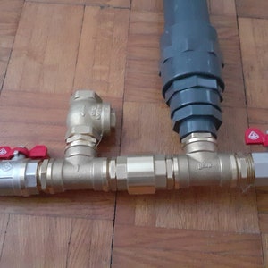 May include: A plumbing system with two brass ball valves with red handles and a gray PVC pipe. The system is connected with brass fittings.