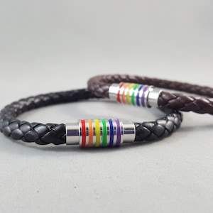 Peut inclure: Deux bracelets en cuir tressé avec des accents métalliques arc-en-ciel. Les bracelets sont noirs et bruns.