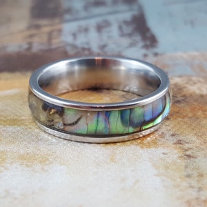 May include: A silver ring with a band of iridescent abalone shell inlay.