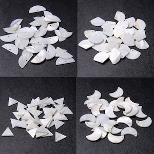 May include: A selection of white shell beads in diverse shapes: half-moons, circles, squares, and triangles. Each bead features a small hole for threading. The beads are displayed on a dark surface, suitable for jewellery making.
