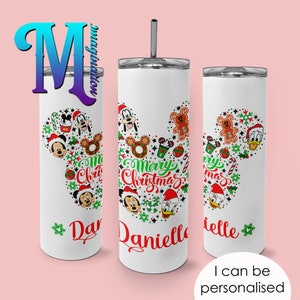 Pode incluir: Caneca branca com tampa e canudo prateados, com um design tem&aacute;tico de Natal. O design inclui Mickey Mouse, Pato Donald e Pateta, juntamente com o texto "Merry Christmas" e um nome. A caneca &eacute; personalizada e tem o texto "I can be personalised".