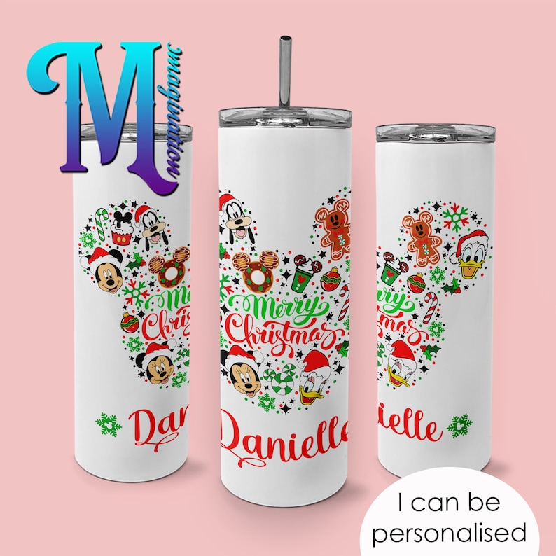 Pode incluir: Caneca branca com tampa e canudo prateados, com um design tem&aacute;tico de Natal. O design inclui Mickey Mouse, Pato Donald e Pateta, juntamente com o texto "Merry Christmas" e um nome. A caneca &eacute; personalizada e tem o texto "I can be personalised".