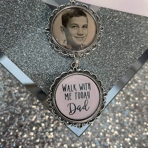 May include: A silver charm with a black and white photo of a young boy and a pink charm with the text "Walk with me today Dad".