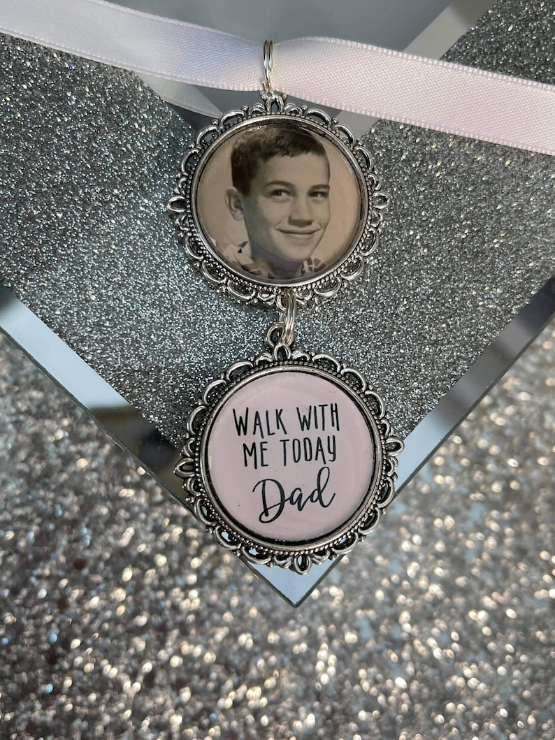 May include: A silver charm with a black and white photo of a young boy and a pink charm with the text "Walk with me today Dad".