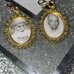 May include: Two gold-toned oval picture frames with ornate edges, each containing a black and white photo of an older man. The frames are attached to gold-toned chains.