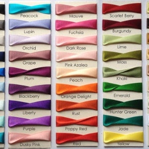 May include: A chart of 36 different colors of satin ribbon, each color is labeled with its name. The colors include black, peacock, mauve, scarlet berry, pale lemon, smoked grey, lupin, fuchsia, burgundy, dark brown, silver, orchid, dark rose, lime, gold, navy, grape, pink azalea, plum, dark royal, peach, khaki, ecru, cornflower, blackberry, orange delight, emerald, sky, liberty, rust, hunter green, bridal white, new turquoise, purple, poppy red, jade, white, malibu blue, dusky pink, red, and yellow.