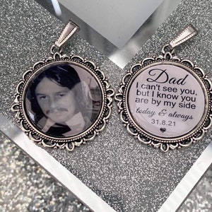 以下が含まれることがあります： 男性の白黒写真が1つ、もう1つには「お父さん、あなたを見ることができませんが、あなたが私のそばにいることは知っています。今日そして永遠に 31.8.21」というテキストが書かれた、2つの銀製のロケットペンダントです。