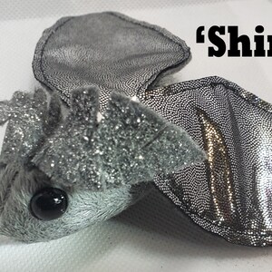 May include: A silver sparkly plush bat with black eyes and a 'shiny' label.