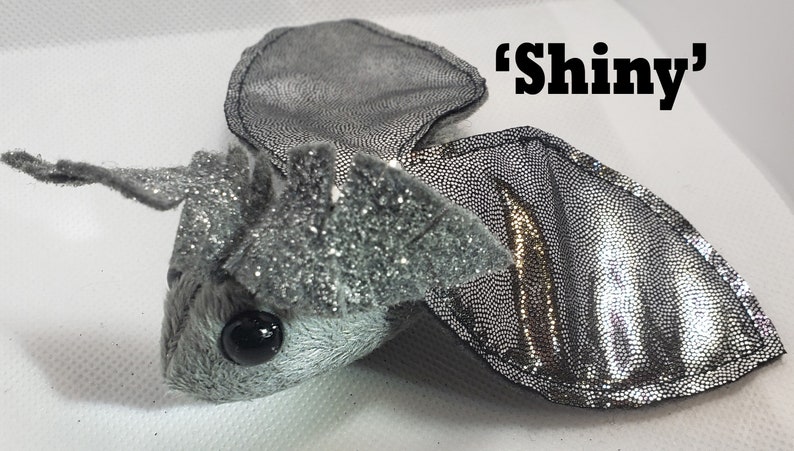 May include: A silver sparkly plush bat with black eyes and a 'shiny' label.