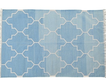 May include: A light blue rug with a white geometric pattern. The rug has fringe on all four sides.