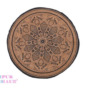 May include: Round jute rug with a black mandala design. The rug has a natural brown color and a black border.