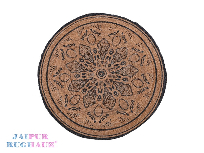 May include: Round jute rug with a black mandala design. The rug has a natural brown color and a black border.