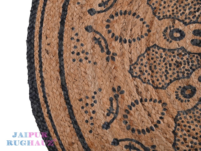 May include: A round jute rug with a black and white geometric pattern. The rug has a black border and is made of natural fibers.