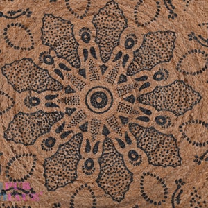 May include: A brown woven rug with a black and white geometric design. The design features a central circle with radiating lines and dots.