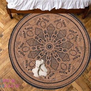 May include: A round jute rug with a black mandala design. The rug is on a wooden floor.