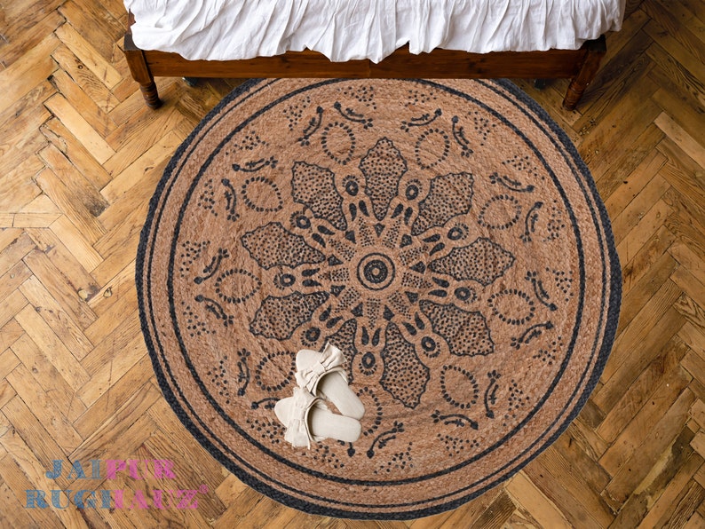 May include: A round jute rug with a black mandala design. The rug is on a wooden floor.