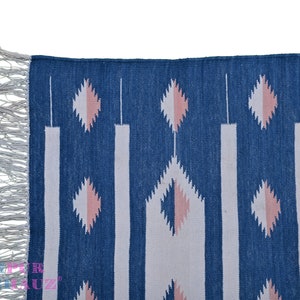 May include: A blue and white woven rug with a geometric pattern and fringe on the edges.