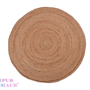 May include: A round, natural fiber rug with a woven texture. The rug is a light brown color and has a circular pattern.