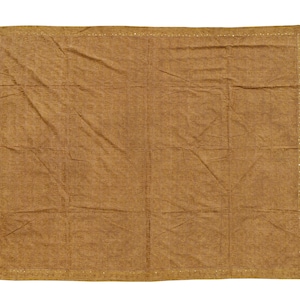 May include: A rectangular, brown textile with a textured surface. The edges are finished with a decorative stitch. The fabric is folded and creased, suggesting it is a blanket or throw.