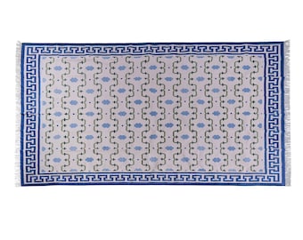 May include: Rectangular area rug with a light background and a repeating pattern of blue cloud-like shapes and green stems. The rug has a blue border with a Greek key design and fringe on the short ends.