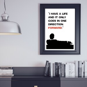 May include: Black and white print of a man sitting in a chair with the quote "I have a life and it only goes in one direction. Forward." in red text.