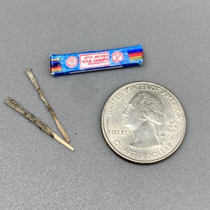 May include: Two incense sticks with a blue and white box of Satya Sai Baba Nag Champa incense. The box is about the size of a US quarter.