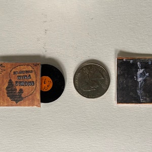 Puede incluir: Una portada de disco de vinilo vintage con el título "Black Gold Nina Simone" y un disco de vinilo negro. También se muestra una moneda de veinticinco centavos de dólar estadounidense de plata y una fotografía en blanco y negro.