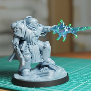 Könnte beinhalten: Eine graue Plastikminiatur eines Space Marines, der eine leuchtend grüne Energiewaffe hält. Die Miniatur ist in einer dynamischen Actionpose aufgestellt und steht auf einem grauen Plastiksockel.