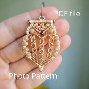 Può includere: Un orecchino a forma di gufo in macramè beige e crema, con un gancio argentato. L'orecchino presenta piccole perline marroni chiare. Il testo "PDF file" e "Photo Pattern" sono visibili.